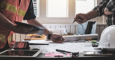 Engineer and surveyor meeting together with plans