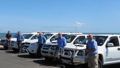 Staff posing with company cars at beach in Redlands